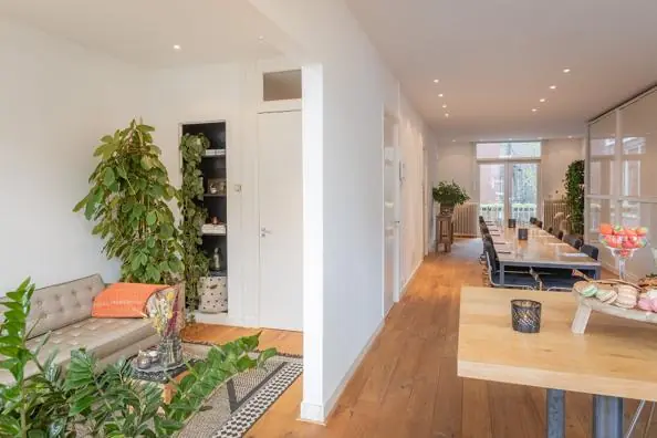 Licht en modern interieur aan de Van Baerlestraat met houten vloer, lange eettafel en veel groen.